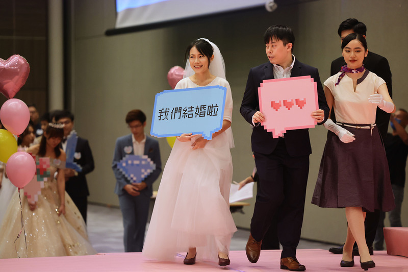 112年台北市聯合婚禮3日在台北南港展覽館2館舉行，新郎、新娘一同拿著標語牌走上舞台，接受各界祝福。中央社記者王飛華攝  112年6月3日 (圖：中央社)