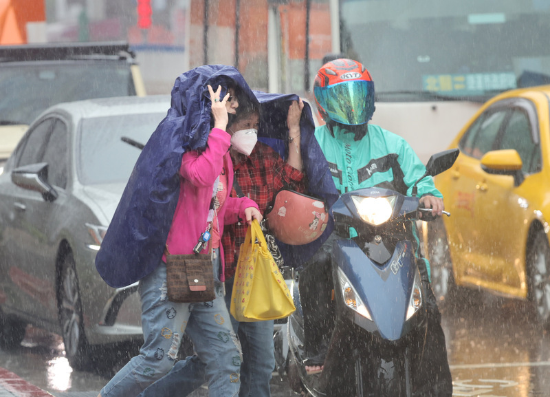 受鋒面影響，台北市區26日中午一度下起大雨，信義區街頭有民眾沒帶雨傘，先以雨衣遮擋頭部，快速通過馬路。中央社記者王飛華攝  113年4月26日 (圖：中央社)